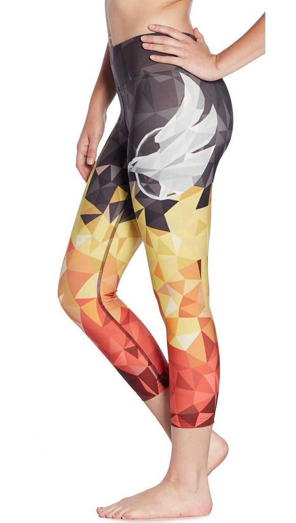close up left side view of model wearing ombre flame polygon themed printed capri leggings with large eagle logo