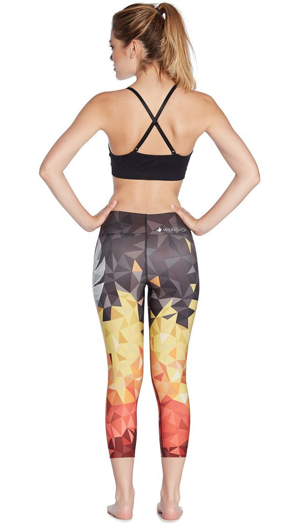 back view of model wearing ombre flame polygon themed printed capri leggings with large eagle logo