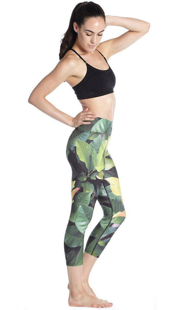 right side view of model wearing tropical foliage themed printed capri leggings