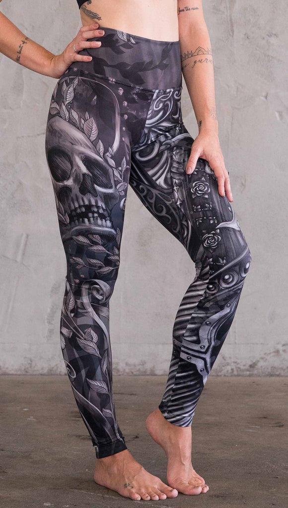 Right view of model wearing the gargoyle mashup leggings in a black and gray color. This leg has a large skull across