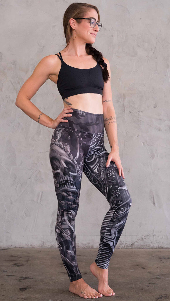 Zoomed out right view of model wearing the gargoyle mashup leggings in a black and gray color. This leg has a large skull across