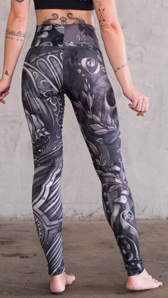 Back view of model wearing the gargoyle mashup leggings in a black and gray color. One leg has a gargoyle and the other leg has a large skull