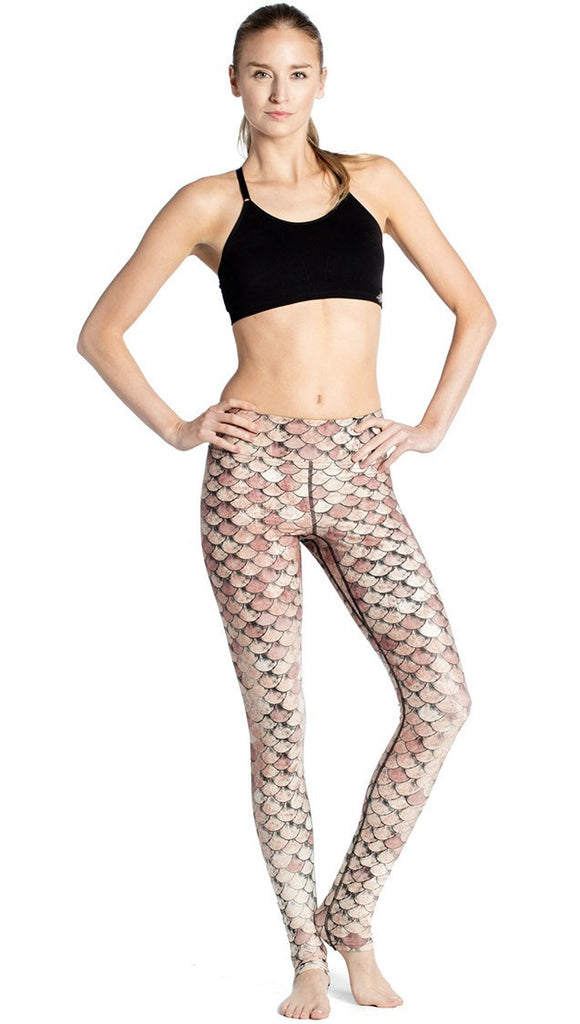front view of model wearing gold mermaid scale themed printed full length leggings
