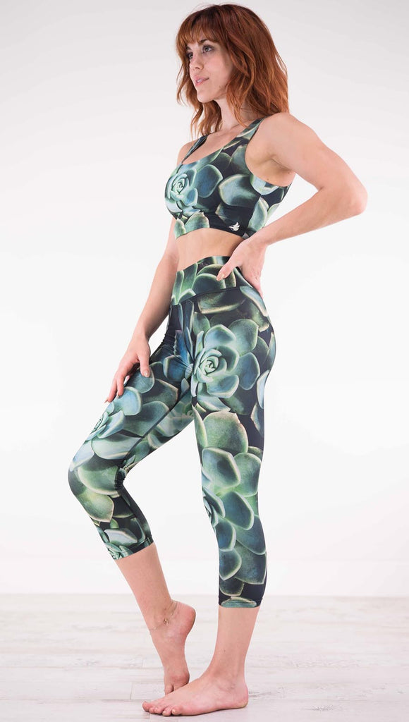 Left view of model wearing black capri leggings with green succulent plants throughout