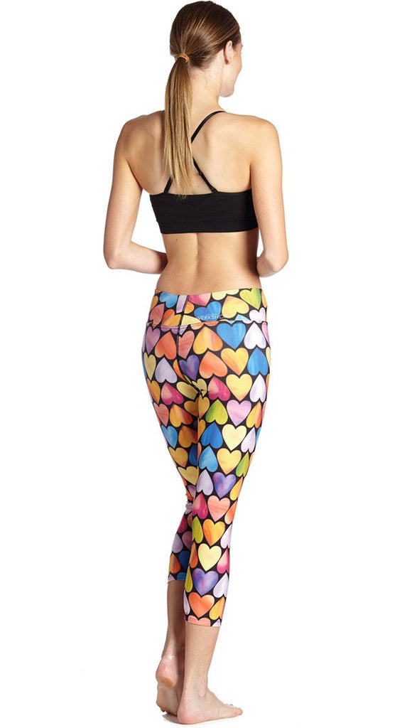 back view of model wearing colorful heart themed printed capri leggings