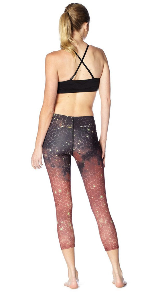 back view of model wearing honeycomb galaxy themed printed capri leggings