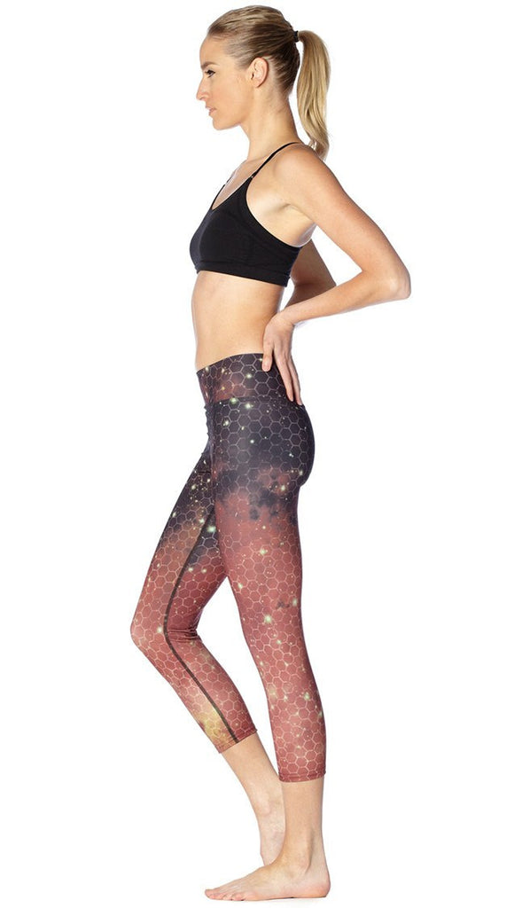 left side view of model wearing honeycomb galaxy themed printed capri leggings