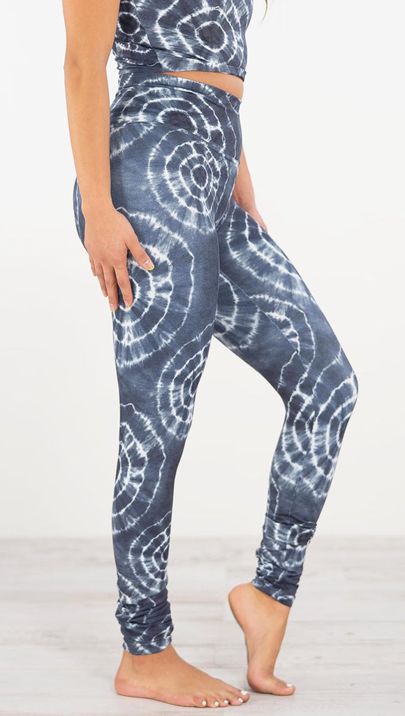 Right side view of model wearing the indigo circles athleisure leggings. They are in a indigo color and have white tie dye circles throughout. Each circle has a smaller circle within each other.