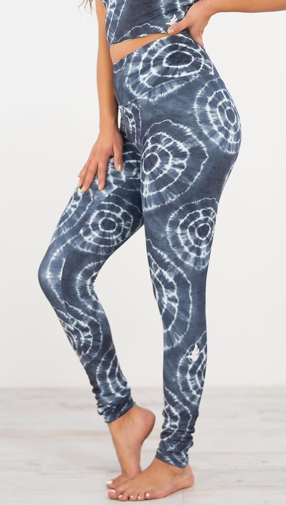 Left side view of model wearing the indigo circles athleisure leggings. They are in a indigo color and have white tie dye circles throughout. Each circle has a smaller circle within each other.