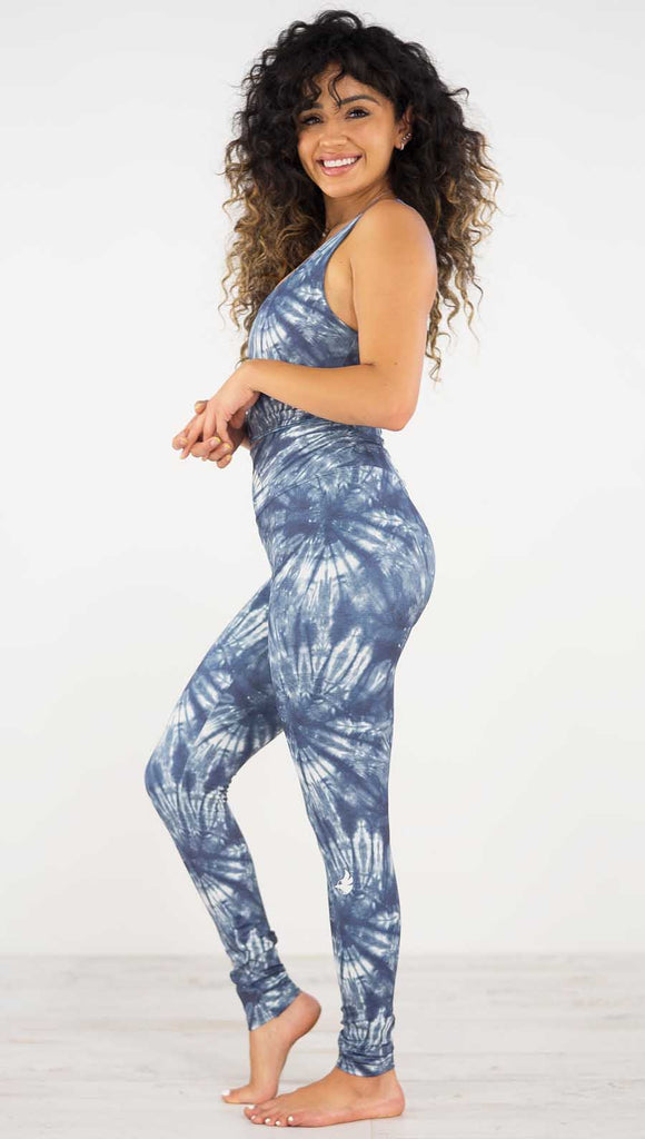 Left side view of model wearing the indigo spiral athleisure leggings. they are in a indigo color and have white tie dye spirals throughout the leggings.
