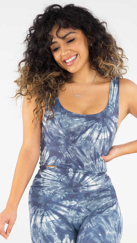 Front view of model wearing the reversible indigo waves/ spiral crop top. This is the spiral side. It is in a indigo color and has white tie dye spiral throughout the top.
