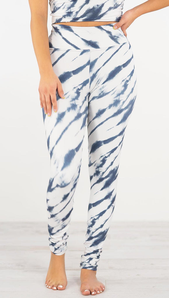 Front view of model wearing the indigo stripes athleisure leggings. They are in a white color with blue zebra-like stripes.