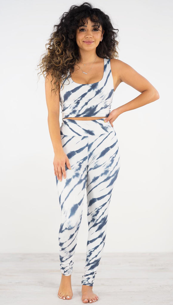 Front view of model wearing the indigo stripes athleisure leggings. they are in a white color and have blue zebra-like stripes.