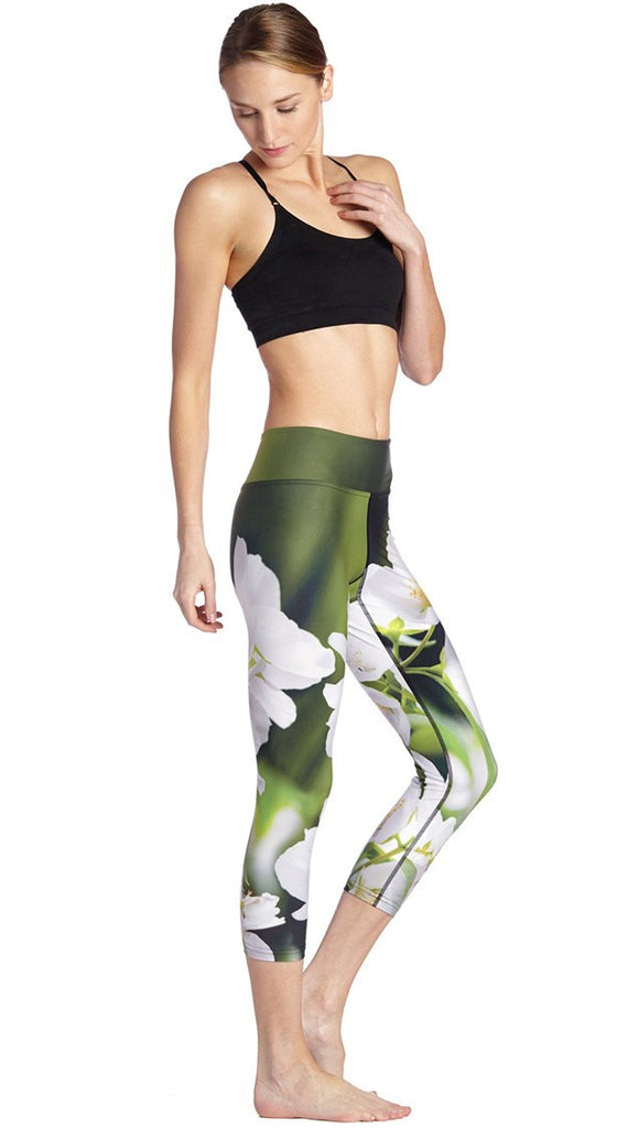 right side view of model wearing white jasmine flower themed printed capri leggings