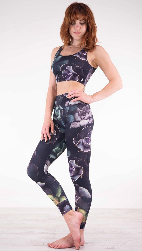 Left view of model wearing black athleisure leggings with green and purple succulent plants throughout