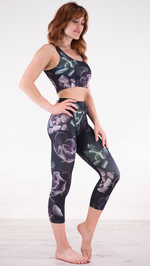 Right view of model wearing black capri leggings with green and purple succulent plants throughout