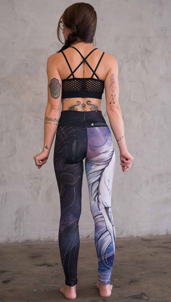 Zoomed out back view of model wearing the nightmare mashup leggings in a blue and dark purple color. One leg has a white unicorn and the other has a black horse with wings