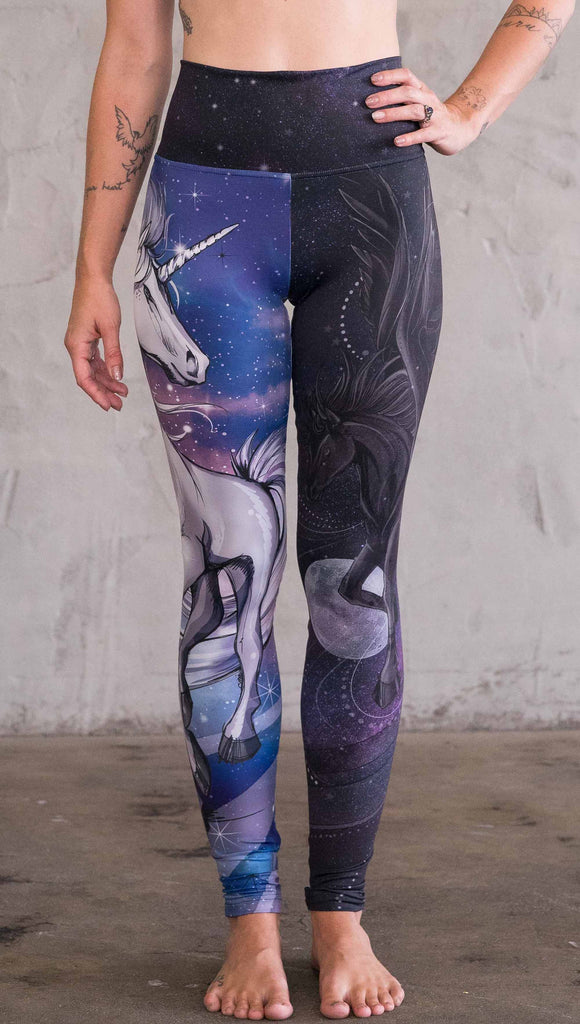 Front view of model wearing the nightmare mashup leggings in blue and dark purple. One leg has a white unicorn and the other leg has a black horse with wings