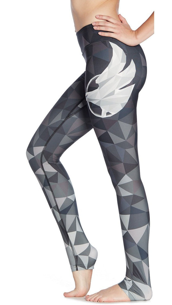 close up left side view of model wearing ombre black polygon themed printed full length leggings with large eagle logo motif