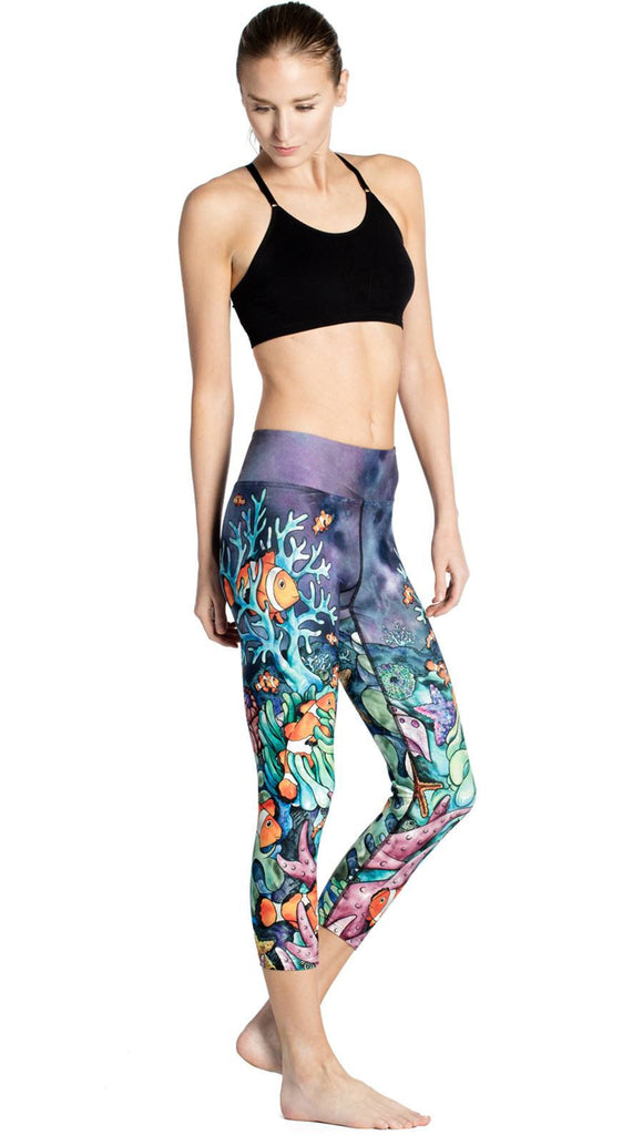 slightly turned front view of model wearing coral reef themed printed capri leggings
