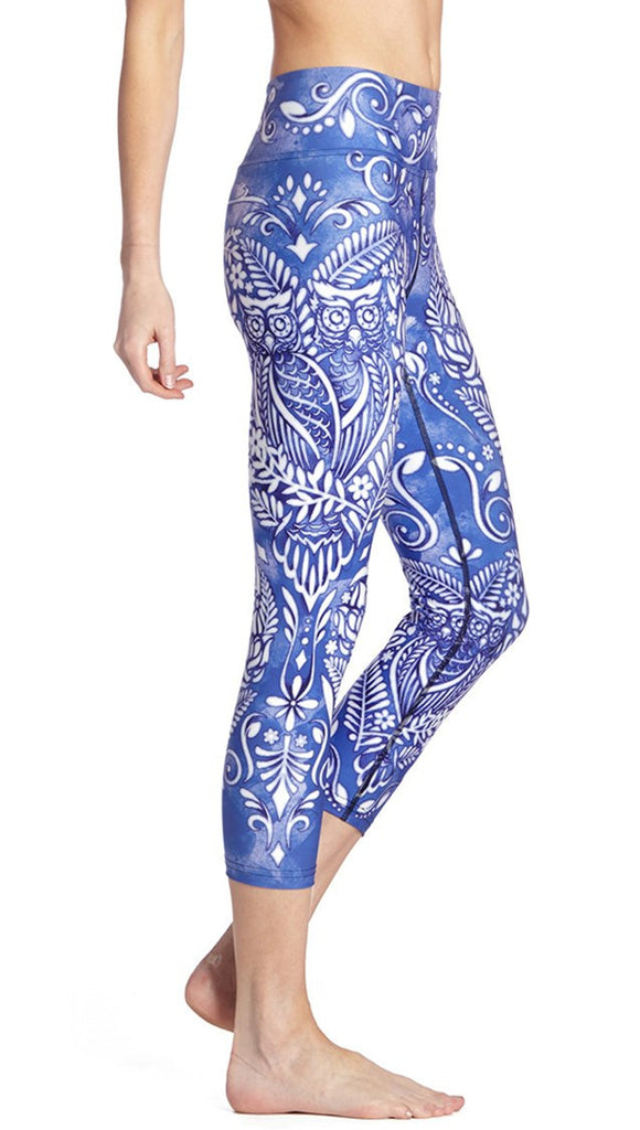 closeup right side view of model wearing blue and white owl themed printed capri leggings