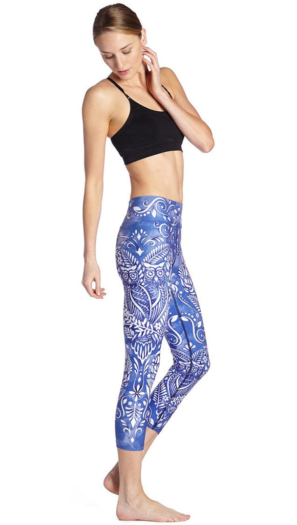 right side view of model wearing blue and white owl themed printed capri leggings