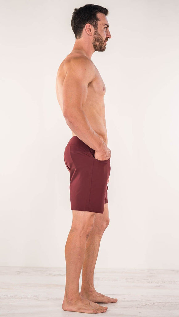 Right side view of model wearing men's oxblood performance shorts with slim fit