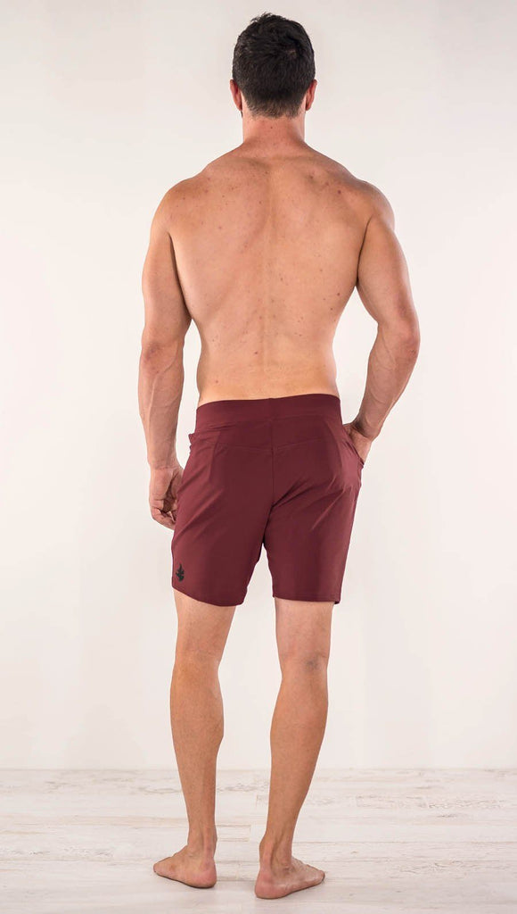 Back side view of model wearing men's oxblood performance shorts with slim fit