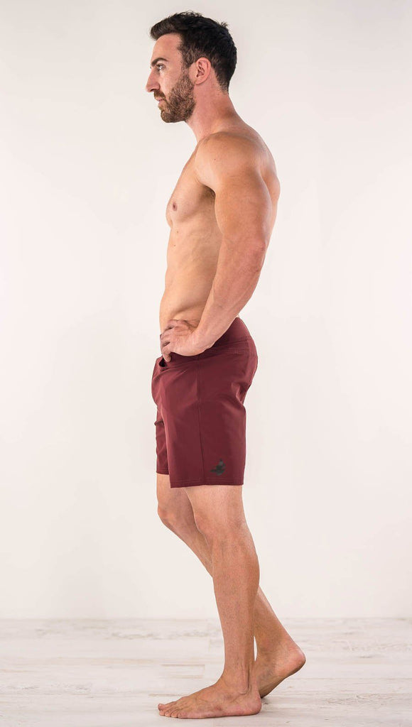 Left side view of model wearing men's oxblood performance shorts with slim fit
