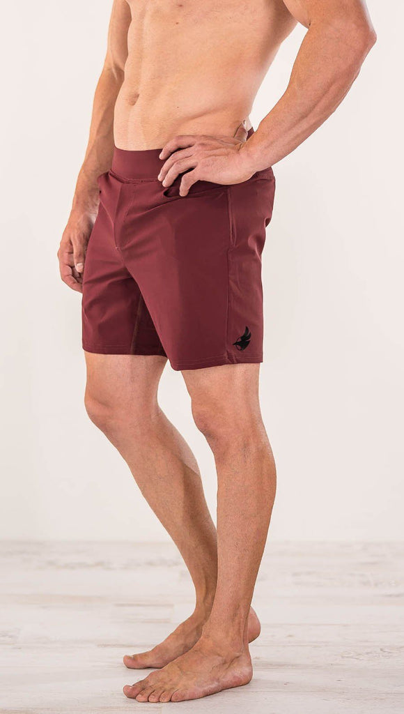 Close up left side view of model wearing men's oxblood performance shorts with slim fit