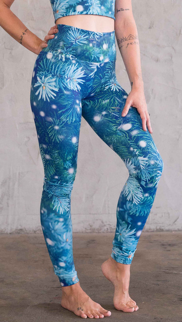 Right view of model wearing blue holiday leggings with flocked pine 
