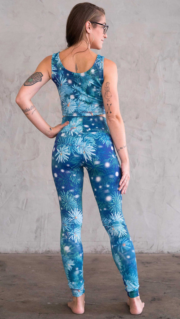 Back view of model wearing blue holiday leggings with flocked pine