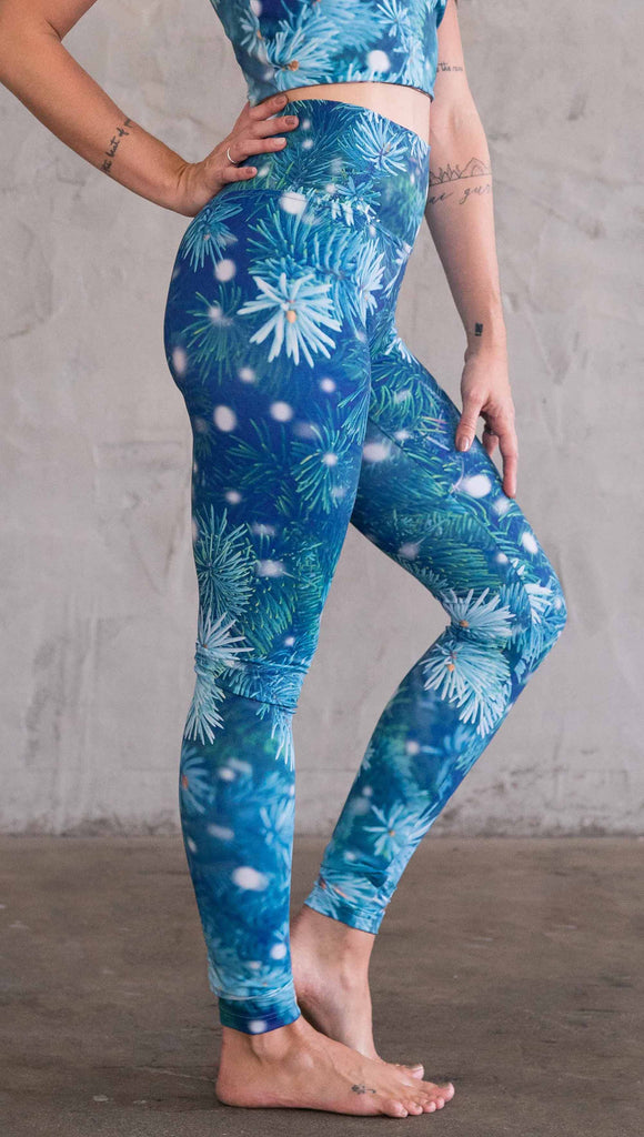 Enhanced right view of model wearing blue holiday leggings with flocked pine