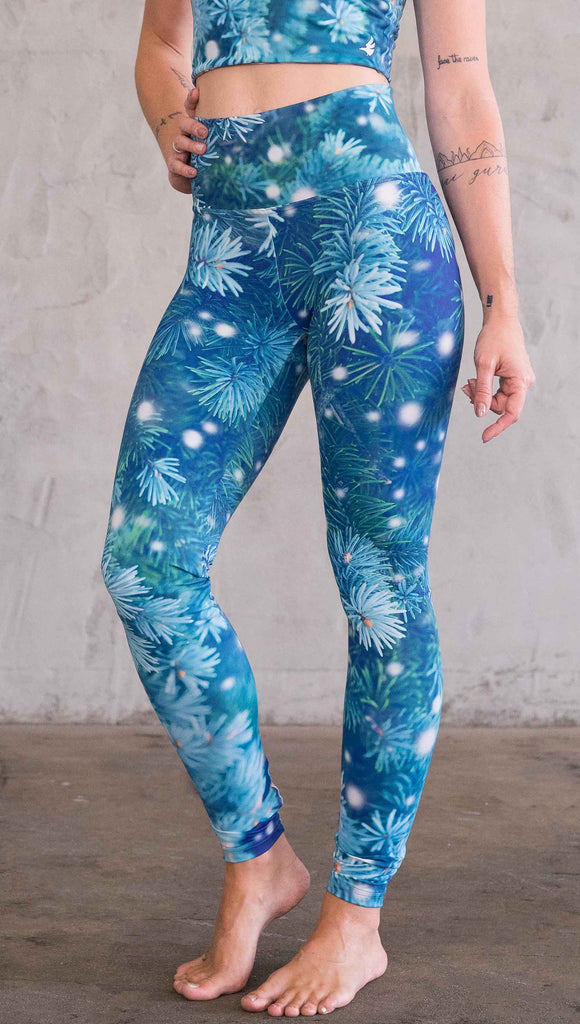Left view of model wearing blue holiday leggings with flocked pine 