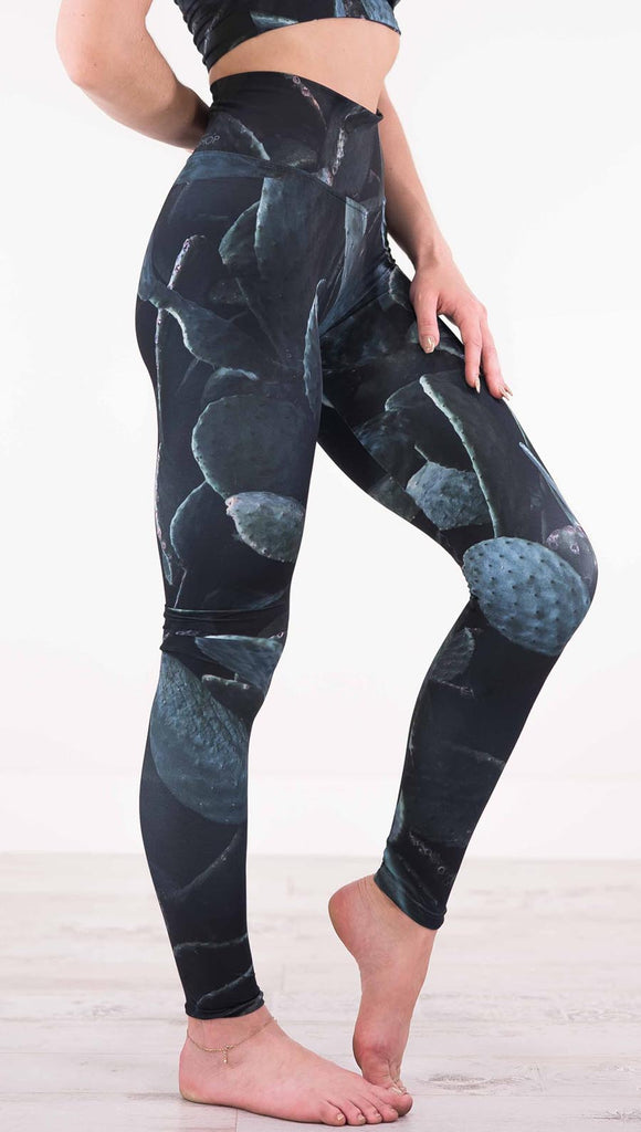 Right view of model wearing black athleisure leggings with dark green cacti plants throughout