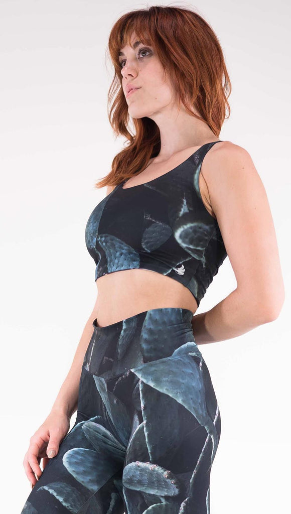 Left view of model wearing the Midnight Garden reversible top. This is in the Prickly Pair side, it is a black crop top with dark green cacti plants throughout