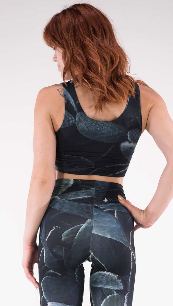Back view of model wearing the Midnight Garden reversible top. This is in the Prickly Pair side, it is a black crop top with dark green cacti plants throughout