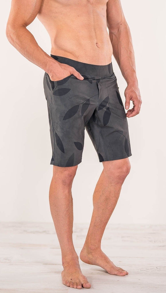 Close up diagonally left side view of model wearing gray printed performance shorts with slim fit and vilva leaf inspired art