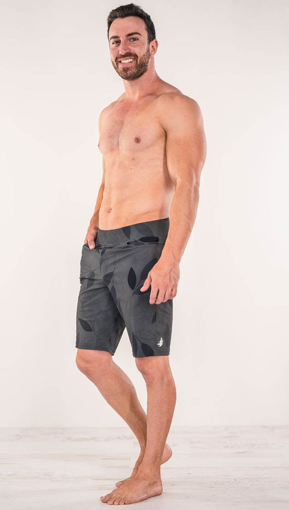 Diagonally left side view of model wearing gray printed performance shorts with slim fit and vilva leaf inspired art