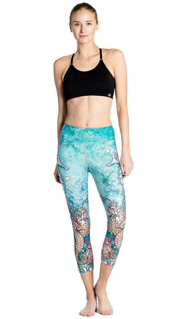 close up front view of model wearing seahorse and coral reef themed printed capri leggings