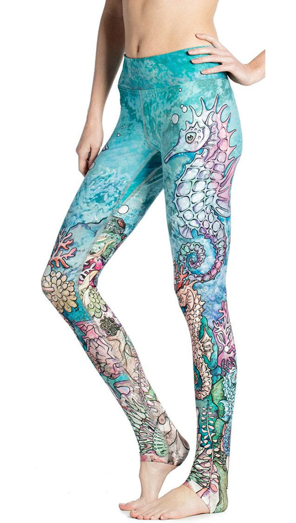 close up left side view of model wearing colorful seahorse themed printed full length leggings