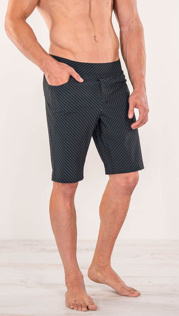 Close up diagonally right side view of model wearing men's black printed performance shorts with slim fit and carbon fiber inspired art.