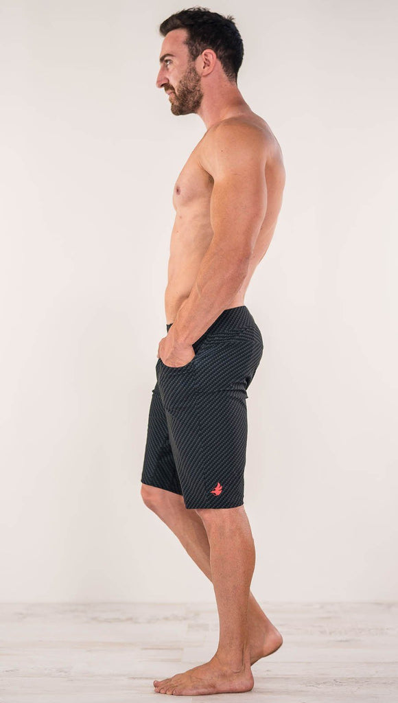 Right side view of model wearing men's black printed performance shorts with slim fit and carbon fiber inspired art.