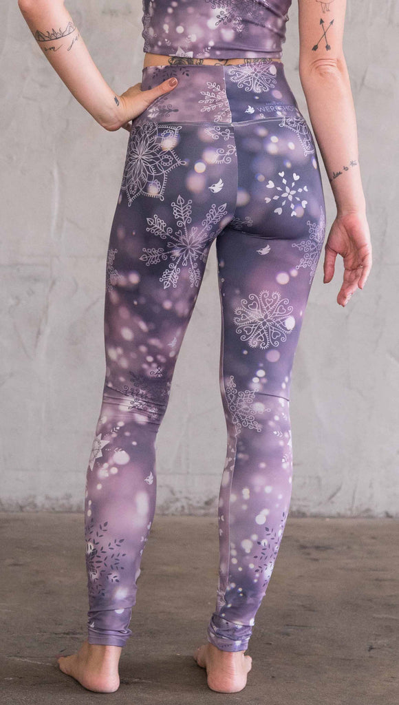 Back view of model wearing purple leggings with white snowflakes
