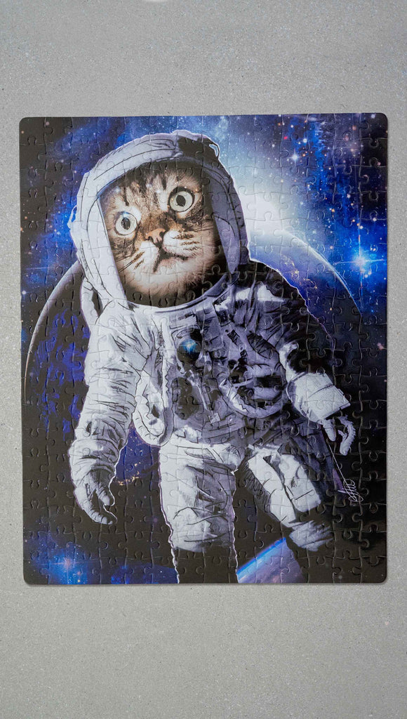 WERKSHOP Space Cat (Catstronaut) Puzzle. The artwork features a house cat wearing an astronaut uniform, floating in outer space with a nebula behind him.