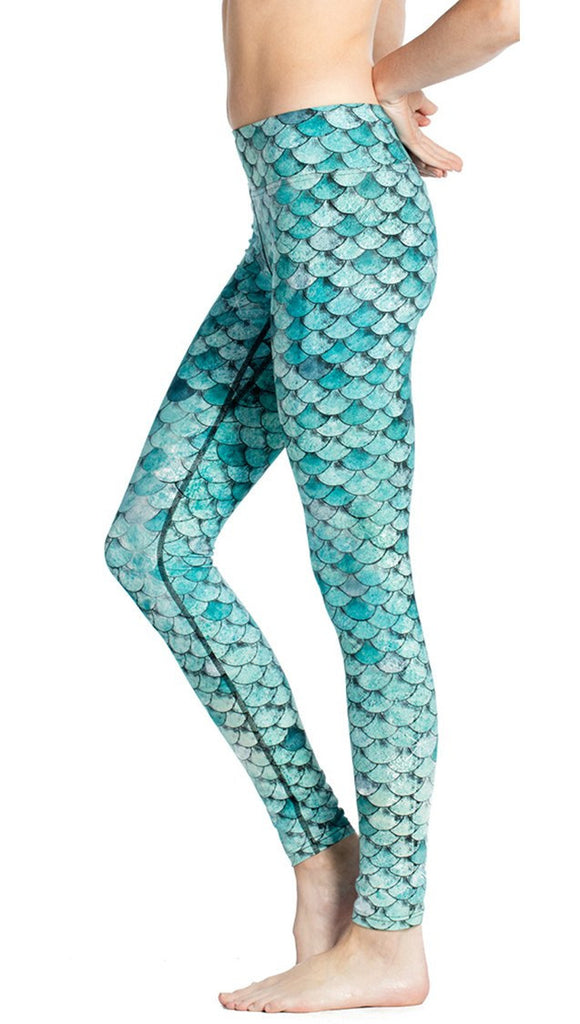 close up left side view of model wearing teal mermaid / fish scale printed full length leggings
