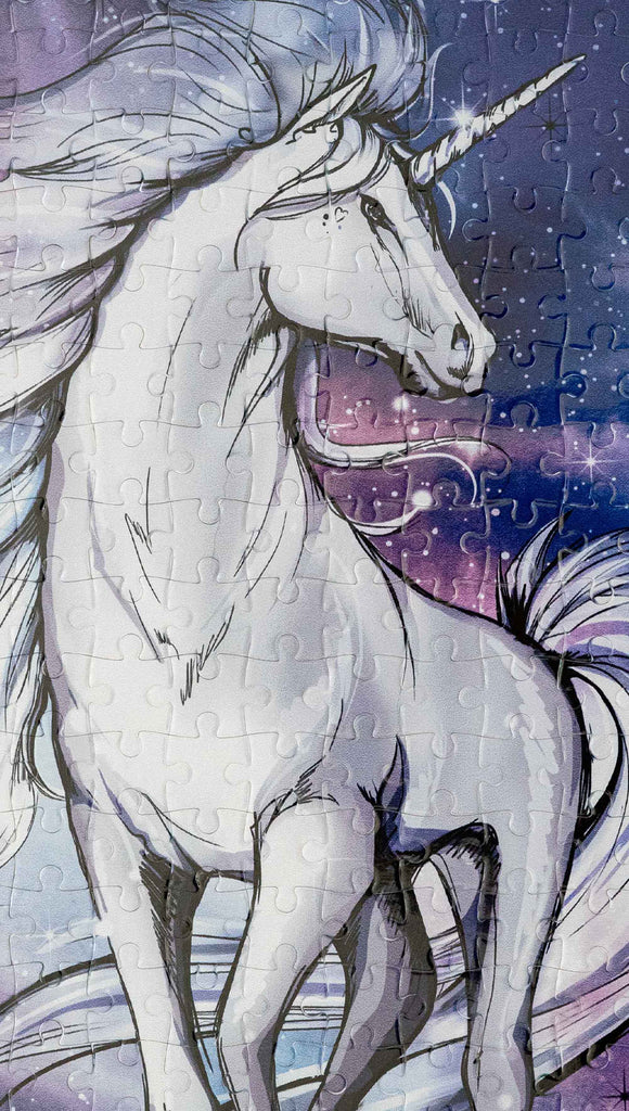 Zoomed in image of WERKSHOP Unicorn 252 piece jigsaw puzzle. The puzzle is printed with original artwork of a Unicorn by Chriztina Marie. It features a white unicorn prancing on a fantastical galactic background with swirls of purple and blue with sparkles. 