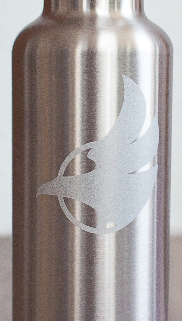 Closeup of silver water bottle with Eagle Rock Werkshop logo resting on a purple yoga mat with Eagle Rock Werkshop logo.