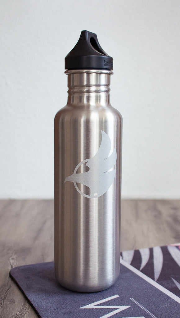 Silver water bottle with Eagle Rock Werkshop logo resting on a purple yoga mat with Eagle Rock Werkshop logo.