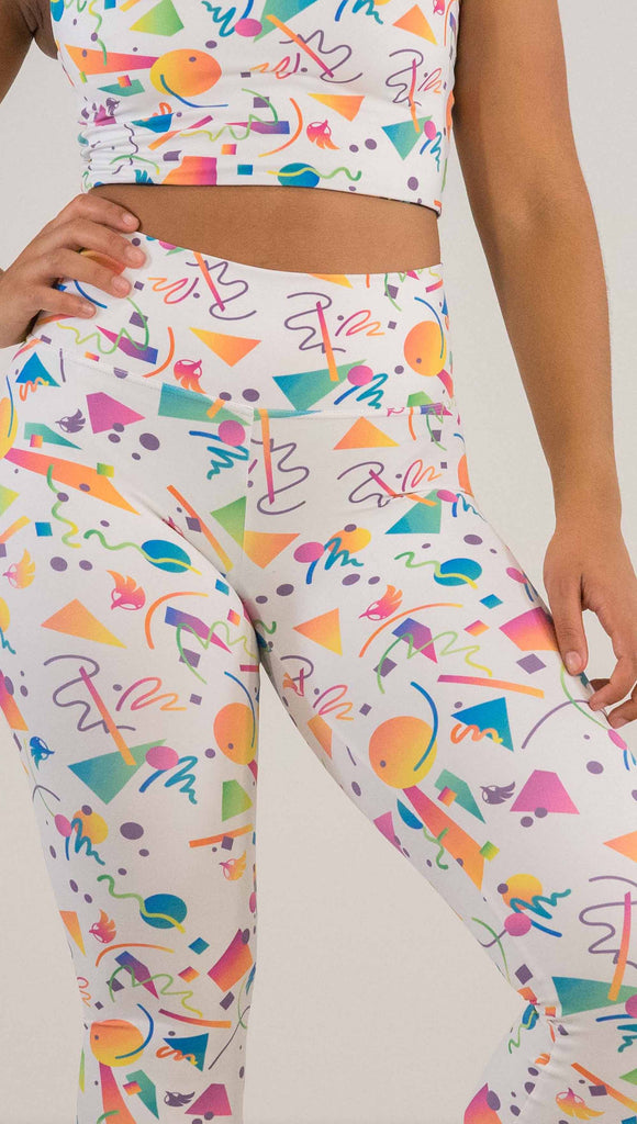 Zoomed in shot of model wearing WERKSHOP white confetti athleisure leggings. The artwork on the leggings shows multi-colored circles, scribbles and triangles over a white background.